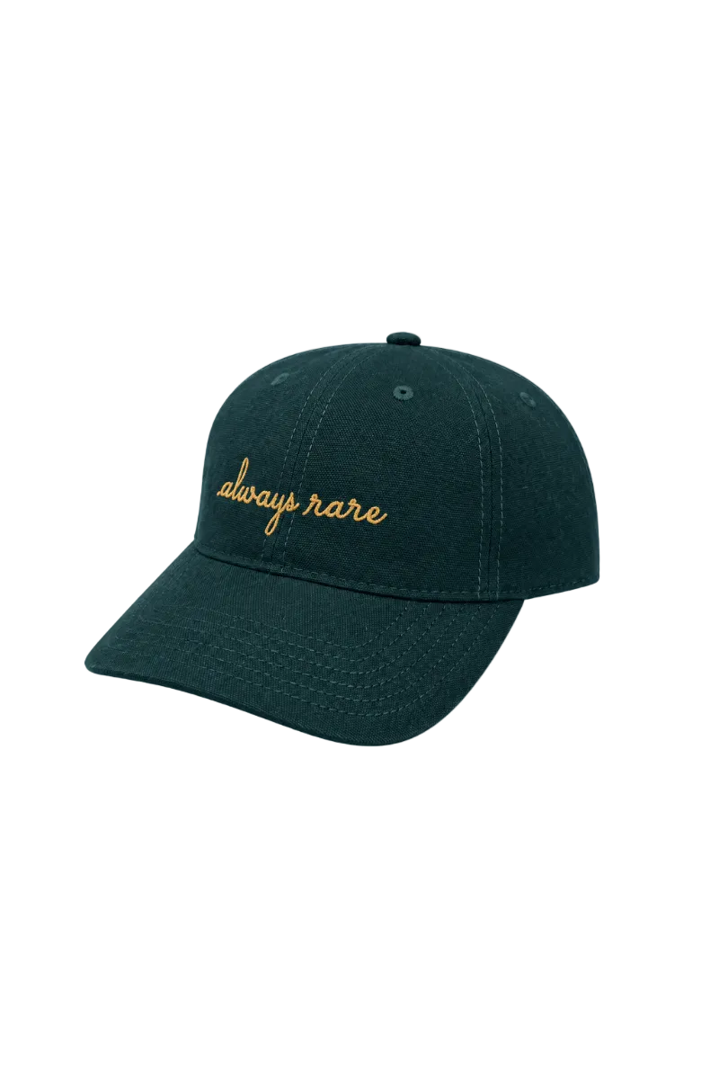 A dark forest green baseball cap with 'always rare' embroidered in gold cursive on the front, shown against a light gray background.