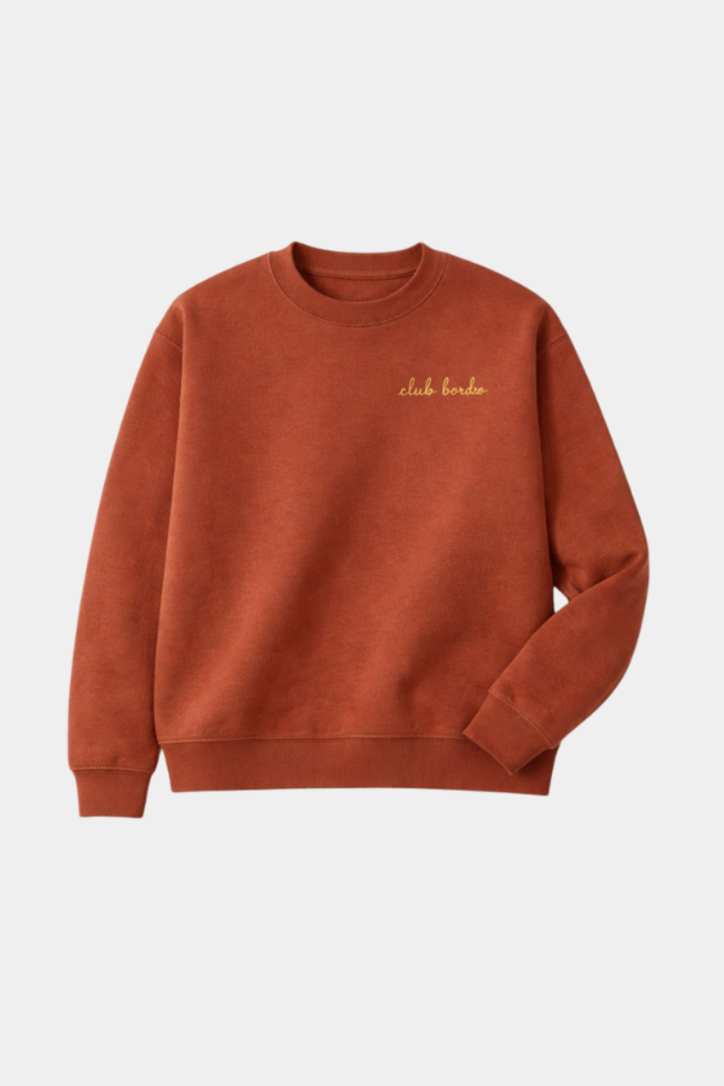 A clay colored crewneck sweatshirt with 'club bardo' embroidered in gold script on the left chest, displayed on a clean light gray background.